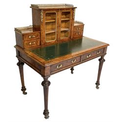 19th century figured walnut lady's writing desk or Bonheur du Jour, raised cabinet enclosed by two glazed doors flanked by smaller drawer, decorated with cast gilt metal mounts and gallery, moulded rectangular top with inset leather over two drawers, turned and fluted supports carved with trailing foliage and terminating to lobe feet, on brass castors