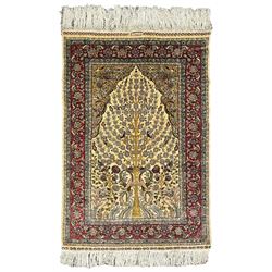 Hereke tree of life design silk rug, the field with tree of life within Mirab, decorated profusely with flower heads and trailing branches, crimson ground guarded border decorated with repeating flower heads and foliate motifs, signature panel to the top outer edge