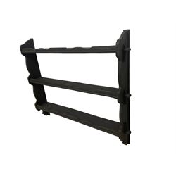 Black painted and wax finish three tier wall rack, the shelves with pegged joints into shaped end supports