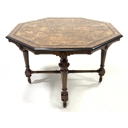 Victorian Aesthetic period centre table, the octagonal burr walnut top with boxwood string inlay, ebonised and amboyna banding and bordered by moulded ebonised edge over shaped apron with applied floral carved roundels, raised on four turned and fluted supports united by cross stretcher, brass and ceramic castors, 114cm x 114cm, H74cm