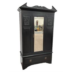 19th century black painted wardrobe, the pointed and scroll carved pediment over panelled and carved front with central bevelled mirror door, drawer to base, on bracket feet