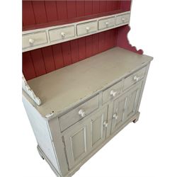 Cream painted dresser, the projecting cornice over two height plate rack with drawers, over three drawers and two cupboard doors, raised on bracket supports 