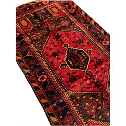Persian Hamadan rug, stepped central lozenge decorated with geometric motifs, repeating border decorated with stylised flower heads, chequered lozenge outer-band