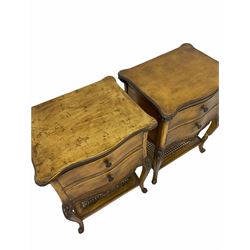 Pair French style gilt bedside tables, the shaped moulded tops over two drawers and shaped apron, floral carved cabriole supports joined by cane under tier 