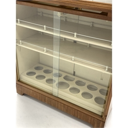 Mid 20th century mahogany illuminated cocktail cabinet, the cross banded and boxwood strung top with inset plate glass over mirrored slide, glazed sliding doors opposite two cupboard doors under, enclosing three shelves, one with bottle recesses, raised on castors 