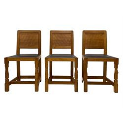 Mouseman - set six oak dining chairs, adzed panelled back, upholstered in navy blue leather with studded band, the octagonal front supports carved with mouse signatures, by the workshop of Robert Thompson, Kilburn