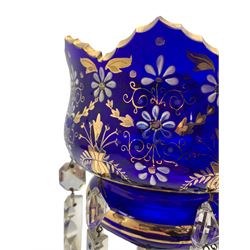 19th/ early 20th century blue glass table lustre decorated with gilt and white enamel flowerheads, the bowl and knopped stem suspending sixteen prismatic drops H37.5cm, displayed within a clear glass dome on oak and beech stepped base H53cm overall