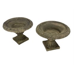 Pair of composite stone classical urn planters, shallow bowl-shaped with egg and dart rim on gadrooned underbelly, fanned foot on square base