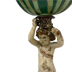 Italian design polychrome carved wood figure depicting Putto holding a shell aloft, shaped shell form basin resting on the head of the putto's coiffure, holding foliage festoon, the raised knee rests upon C-scroll decorated with foliage, berries and flutes, waisted circular form base in the form of shells with moulded upper edge over carved S-scrolls, on four C-scrolled foliage feet 