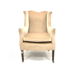 Edwardian wing back easy chair, upholstered in faded velvet, with squab cushion, raised on square tapered supports terminating in ceramic castors W66cm
