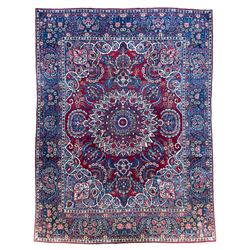 Antique Persian crimson ground carpet, the central floral pole medallion with extending garlands and palmettes, the indigo spandrels with ivory trailing vines and flower heads, the multi-band border decorated with repeating stylised plant motifs and rosettes