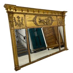 Regency giltwood and gesso overmantel mirror, projecting cavetto cornice decorated with globular mounts, the central frieze panel decorated with Classical chariot scene within foliate borders, the flanking panels with lyres and trailing oak leaf and acorns, three bevelled mirror plates enclosed by reeded half columns with Composite capitals