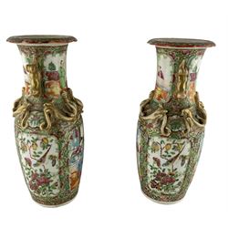 Pair of 19th century Chinese Canton Famille Rose vases, each hand painted with panels enclosing attendants and exotic birds, all reserved on a gilt-ground of dense lotus scrolls, with applied Dog of Fo handles and relief motifs to the necks, H26cm