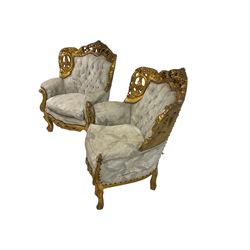 Pair Louis XVI design gilt wingback armchairs, the ornate cresting rail pierced and carved with scrolling foliate decoration and flower heads, the apron decorated with a central moulded and pierced cartouche, raised on cabriole supports, upholstered in buttoned pale blue damask fabric with sprung seat