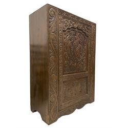 Late 19th century gothic revival oak freestanding cupboard, the front carved with lunette frieze, the panelled door heavily carved with a central heraldic crest with unicorn over a shield, flanked by scrolling foliate decoration, fitted with two shelves, raised on shaped plinth base