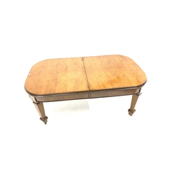 Early 20th century walnut extending dining table, quarter sawn veneered top with carving to edge, raised on square tapered supports with rounded peg feet, brass castors, without additional leaf, 181cm x 105cm, H75cm