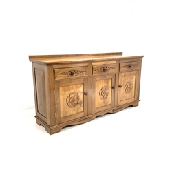 Yorkshire oak sideboard, three drawers over three fielded panelled cupboards each carved with Yorkshire rose roundels, raised on shaped bracket supports 