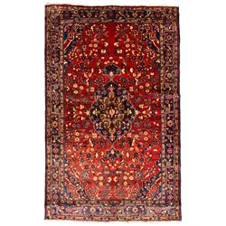 Persian crimson ground rug, the indigo floral pole medallion within a busy field of swirling branches with flower heads and stylised plant motifs, the multi-band border with geometric floral symbols 