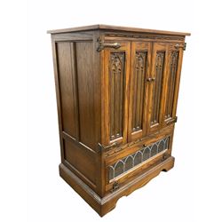 Old Charm - 20th century oak Hi - Fi / record cabinet, fitted with two bi fold doors carved with gothic arches over lead glazed fall front door under, raised on skirted base W71cm, H97cm, D49cm