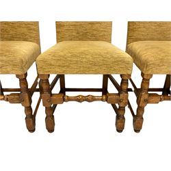 Set eight oak framed dining chairs, high arched back and seat upholstered in light ochre fabric, on turned supports joined by turned front stretcher, with visible peg joints