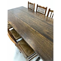 20th century medium oak refectory style dining table, the rectangular top raised on shaped panel end supports united by pegged stretcher (184cm x 87cm, H77cm) together with a set of six spindle back dining chairs with string seats, raised on turned supports
