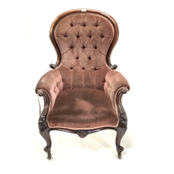 Victorian mahogany armchair, upholstered in deep buttoned velvet, with scroll and floral carved arm terminals over cabriole supports and brass castors, 