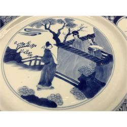 Chinese Kangxi plate decorated in blue and white with a figure looking over a wall with two figures in a garden, the border with further panels of figures, the reverse with six character mark D27cm