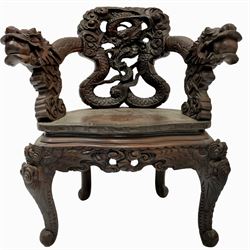 Japanese Meiji period open armchair, the back carved and pierced with dragon and scrolling scaled tails, projecting dragon carved arm terminals on scrolled supports, serpentine seat with decorative band, the apron and supports with scroll and chip-carved decoration