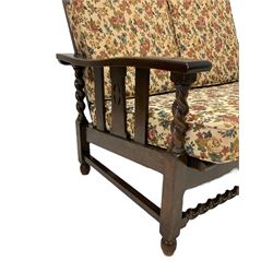 Early to mid-20th century oak framed two seat reclining sofa, slatted back and seat, spiral turned arm supports, raised on square legs with barley twist front stretcher, the loose cushions upholstered in floral patterned fabric