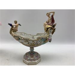 19th century Milan San Cristoforo navette shape centrepiece in the form of a cherub on a dragon accompanied by a female figure, painted with masks, dragons etc and on a pedestal foot H30cm x L29cm and another of very similar design