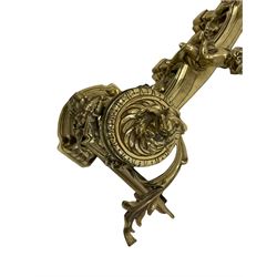 An Impressive 19th century brass fire fender, each end cast with a festooned urn above a snarling lion mask, flanking the pierced and floral swag centre, mounted with Putti, L145cm, H43cm, D38cm 