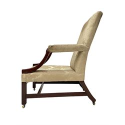 George III mahogany Gainsborough armchair, wide seat and back upholstered in pale green damask fabric, the curved arm supports with turned roundels to terminals, raked back with out splayed supports and square front supports joined by plain stretcher rails, on brass castors