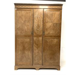 Early 20th century veneered double wardrobe, projecting cornice over frieze with inlaid mother of pearl decoration, two doors enclosing interior fitted with 'Everitt's patent' hanging system and three drawers, the doors with radial cut veneers, raised on shaped plinth base W150cm, H211cm, D49cm