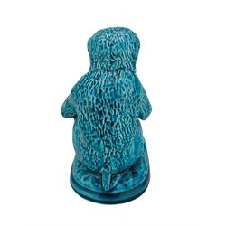 Burmantofts Faience turquoise-glaze model of a monkey, modelled seated resting on a vase, his foot resting on a large nut, on fluted oblong base, impressed factory marks beneath, model no. 782, H15cm x L16cm