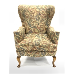 20th century wing back armchair, with swept arms, squab cushion upholstered in scrolled floral fabric, raised on cabriole front supports