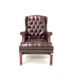 20th century George III style wing back armchair, upholstered in deep buttoned and studded ox blood leather, raised on square chamfered supports 