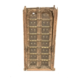  Pair northern Indian teak and metal bound doors, with carved detail and decorative brass studding, in original frame, 70cm x 138cm  