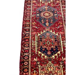 Persian red ground runner, decorated with six trailing geometric medallions, the field decorated with small stylised motifs, thee band border with geometric design