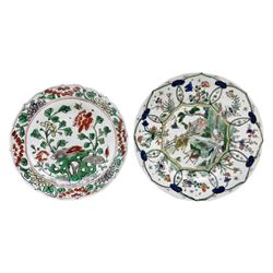Chinese Kangxi porcelain plate decorated in Famille Verte enamels with three deer on a fenced veranda, Ding incense burner mark beneath D22cm, and another Chinese Famille Verte plate with Conch shell mark beneath (2)