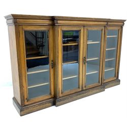 Maple & Co - Late Victorian dwarf breakfront bookcase, moulded cornice over leaf carved cushion frieze, four bevel glazed doors enclosing eleven shelves, flanked by fluted pilasters, raised on plinth base, bearing Ivorine makers label W199cm, D44cm, H122cm