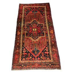 Persian indigo ground rug, the central geometric medallion within a red field surrounded by interconnected geometric flowerheads, the indigo spandrels filled with stylised plant motifs, the guarded border decorated with repeating patterns