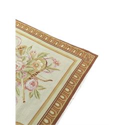 French Aubusson rug, central floral oval panel within a bay leaf band, the spandrels decorated with flowers and musical motifs