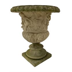 Composite stone Campana shaped garden urn, the egg and dart edge over a relief frieze depicting mischievous putti and bacchic celebration, the gadrooned bowl with horned satyr masks