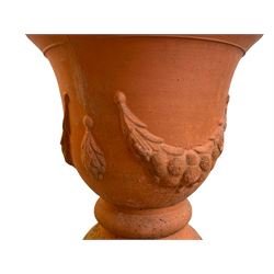 Pair of terracotta garden planters on pedestals, urn-shaped planters decorated with festoons, on twist pedestals with circular moulded footed base