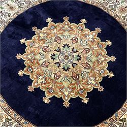Persian Kashmir ivory ground silk pile circular rug, the solid indigo field decorated with a central floral medallion, the banded border with repeating interlacing palmette motifs