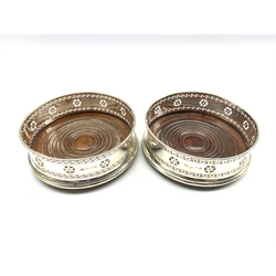 Matched pair of silver bottle coasters with pierced decoration and turned mahogany bases D13cm Birmingham 1867 and 1899 Maker George Unite