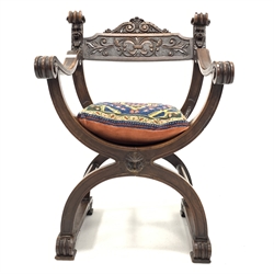 Early 20th century walnut 'X' framed chair, with floral and mask carved cresting rail and scrolled open arms, needlework squab cushion, scrolled supports, W56cm