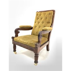 Victorian mahogany open armchair, upholstered in green buttoned velvet, with scroll carving to arm terminals, raised on turned and reeded front supports with later brass cup castors W73cm