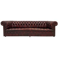Chesterfield four seat sofa, upholstered in buttoned back red leather, raised on castors 
