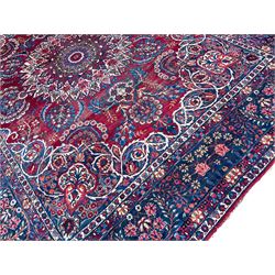 Antique Persian crimson ground carpet, the central floral pole medallion with extending garlands and palmettes, the indigo spandrels with ivory trailing vines and flower heads, the multi-band border decorated with repeating stylised plant motifs and rosettes